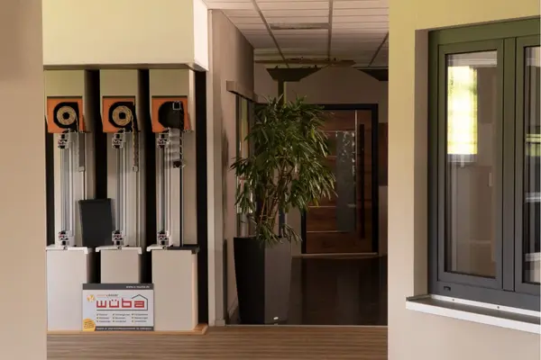 Moderne Ausstellung für Fenster und Türen mit Testgeräten und grüner Zimmerpflanze.