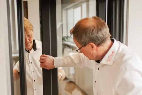 Zwei Männer prüfen gemeinsam eine moderne Schiebetür im Innenbereich eines Hauses.